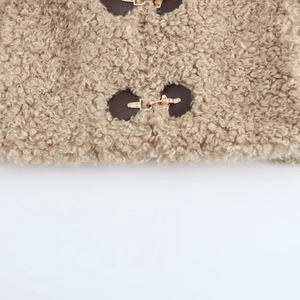 Detail of soft beige fleece texture with gold metal buckle and brown leather accent