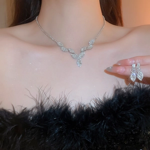 Close-up of sparkling silver V-shaped fringe necklace and earrings with rhinestones
