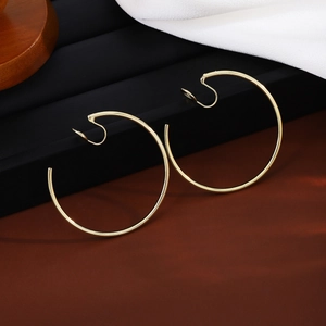 Macro shot of large polished gold clip-on hoop earrings on silk and display stand