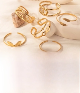 Macro view of gold plated titanium steel open bracelets with feather and leaf motifs