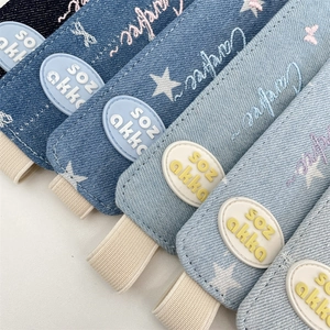 Detail of denim elastic pen pouch band with star embroidery and Carefree lettering