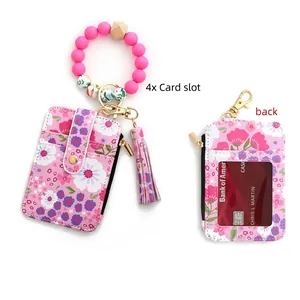 Pink floral card wallet with silicone beaded wristlet and tassel detail close-up
