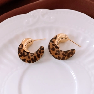 Détail de boucles d'oreilles C plaquées or 18 carats avec texture léopard sur céramique