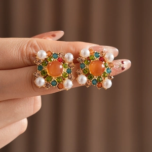 Boucles d'oreilles vintage dorées avec pierre orange, cristaux et perles en gros plan