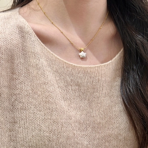 Détail du collier étoile dorée et nacre blanche porté par un mannequin