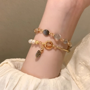 Double-layered beaded bracelet featuring faux pearls, crystals, and gold-tone metal charms