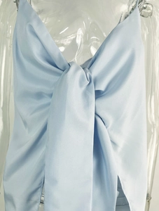 Detail of light blue satin top featuring a large bow tie design and glossy fabric texture