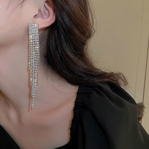 Detailed view of long silver fringe earrings with rows of diamonds on a model