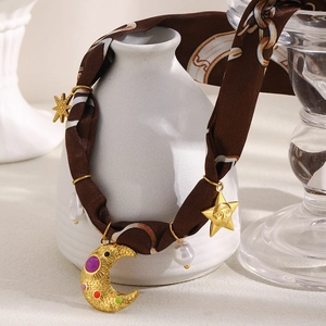 Detail of vintage 18K gold plated charms with moon and star on a brown silk scarf necklace
