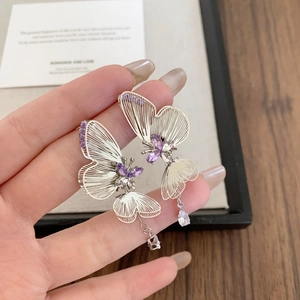 Elegant silver butterfly earrings with purple crystals and teardrop pendants on hand