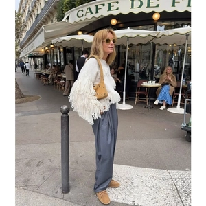 Fashionable hollow shoulder bag in light brown worn with white tassel sweater and suit pants