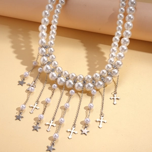Gros plan d'un collier de perles double couche avec pendentifs étoile et croix argentés
