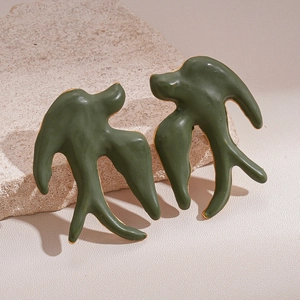 Détail de boucles d'oreilles oiseaux vintage vert foncé et or sur socle pierre