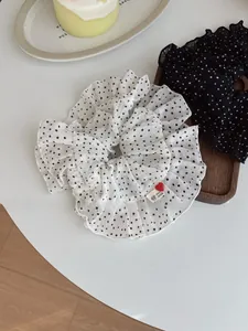 Detailed view of polka dot ruffle scrunchies with heart buttons on white background