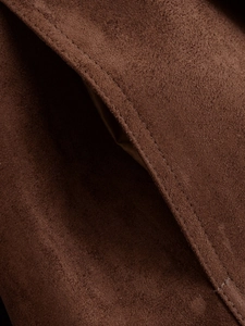 Macro shot of stitching detail and suede texture on dark brown tailored jacket pocket