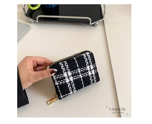 Close-up of black and white tweed coin purse with golden zipper held in hand