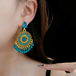Detailed view of vintage gold-tone earrings with turquoise beads on model