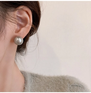Close-up of elegant silver-gray pearl stud earring worn on ear with minimalist style