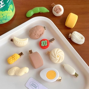 Flat lay of cute food-shaped hair clips including dumplings and eggs on a white tray