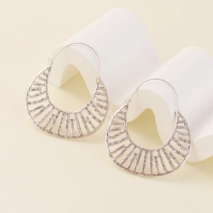 Silver hollow fan-shaped earrings with vintage design on minimalist display stand