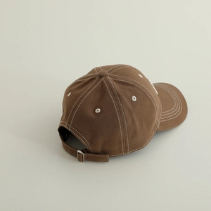Détail de la casquette en coton marron foncé avec coutures blanches et boucle métallique