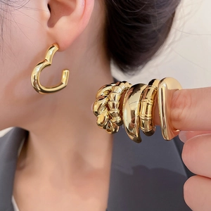 Close-up of assorted gold geometric drop earrings and twisted metal textured studs