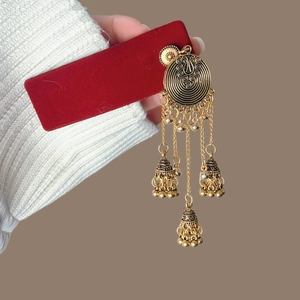 Boucles d'oreilles ethniques dorées avec pampilles et clochettes sur carte rouge