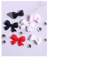 Detailed view of 3D resin bow-shaped nail charms in black, white, red, and pink colors