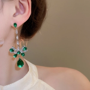 Detail of silver drop earrings with green gemstones and elegant tassel on a model