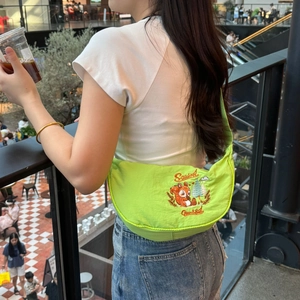 Detail of green nylon crescent bag featuring cute squirrel embroidery and logo
