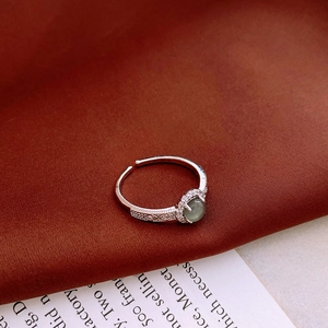 Detailed macro view of retro silver ring with green stone and zircon on red silk
