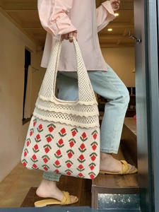 Detail of hand-knitted tote bag featuring red strawberry patterns and openwork weave