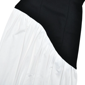 Detailed view of the contrast between black smooth fabric and white pleated texture on the dress