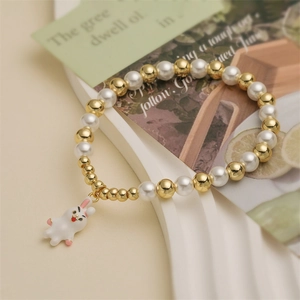 Bracelet mignon avec pendentif lapin en émail, perles et billes dorées sur support