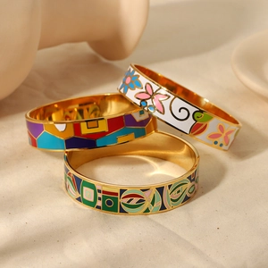 Three colorful enamel gold-plated bangles with abstract artistic patterns on white fabric