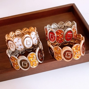 Macro view of vintage enamel oval stretch bracelets with G logo on wooden tray