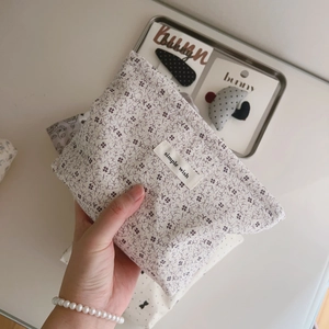 Detail of light gray floral cotton makeup bag with white label and purple flower patterns