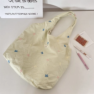 Détail du sac cabas en toile à carreaux avec nœuds brodés et étiquette tissée
