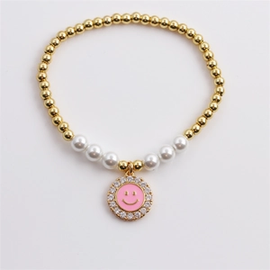 Close-up of pearl and gold bead bracelet featuring a pink zircon smiley face charm