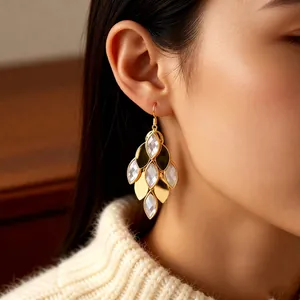 Vintage layered gold leaf drop earrings with white crystals on a model