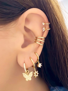 Close-up of gold butterfly and star earrings with cubic zirconia ear cuffs for stacked look