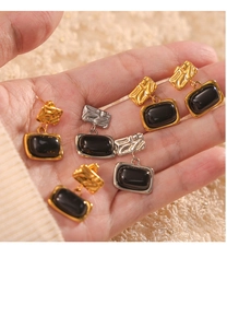 Detail view of vintage British style rectangular gold and silver earrings on a hand