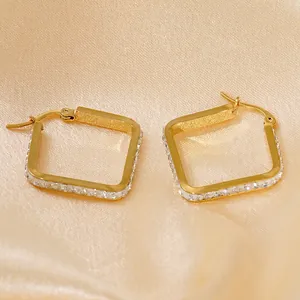 Square gold hoop earrings with sparkling rhinestones on champagne satin background