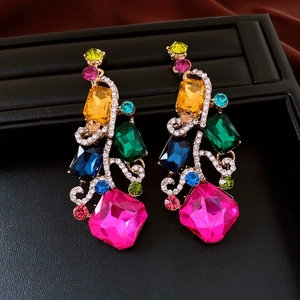 Macro detail of colorful rhinestone square drop earrings on a black jewelry box