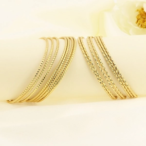 Detail of slim gold bangles featuring a textured grainy finish and stackable design