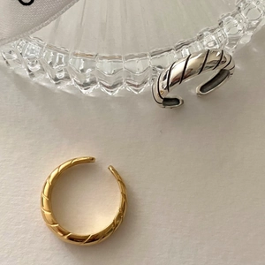 Detail of twisted textured adjustable ring in gold and silver finish on white background