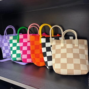 Detailed row of various colorful checkered knit tote bags on a wooden shelf display