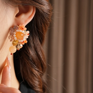 Détail de boucles d'oreilles florales avec perles orange portées par un mannequin de mode