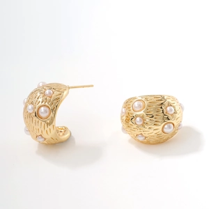 Golden hoop earrings with white pearls and a brushed hammered texture on white background