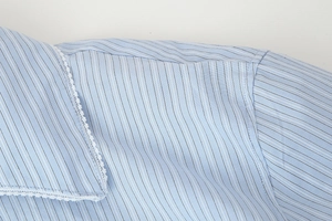 Close-up of blue striped cotton shirt featuring delicate white lace trim on the collar